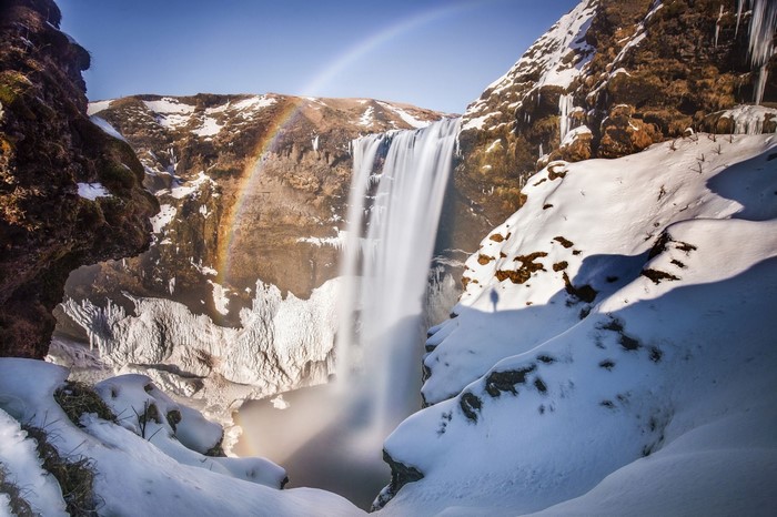 Skogafoss Waterfall in Iceland with Rainbow and Snow