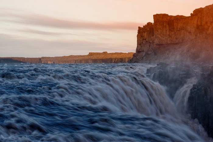 Powerful waterfall cascading over cliffs at sunset