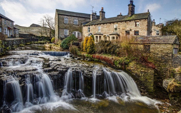 Village with waterfall and stone buildings in England