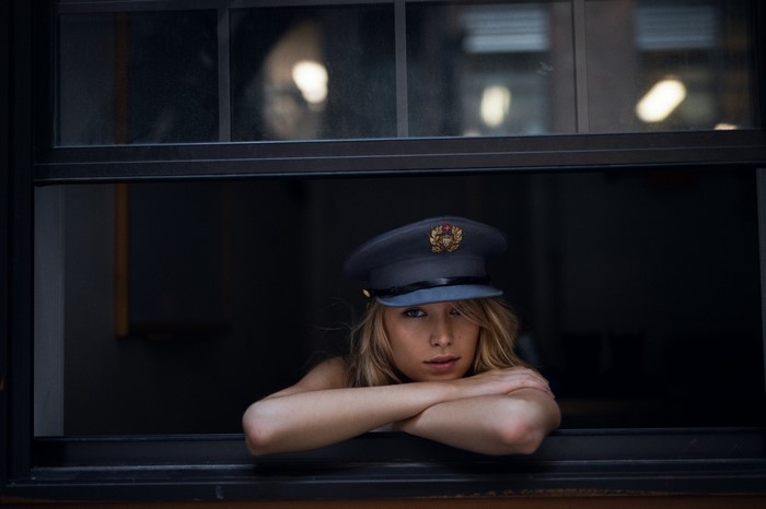 Woman in a military-style hat looking out a window