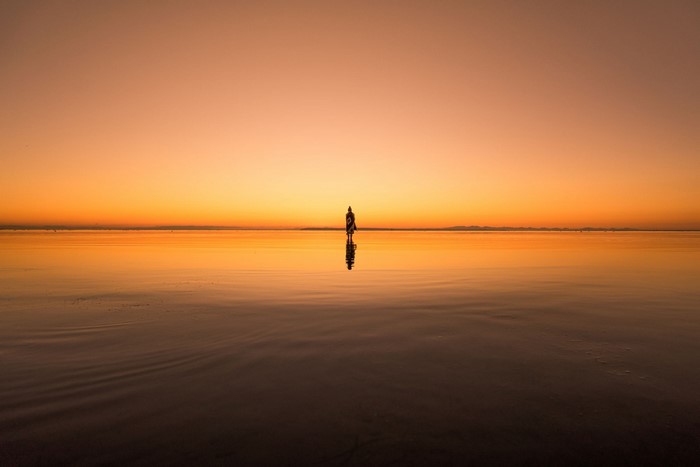 Woman standing in the ocean at sunset