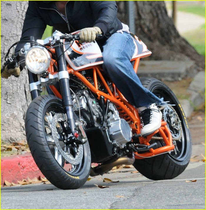 Person riding a custom orange motorcycle