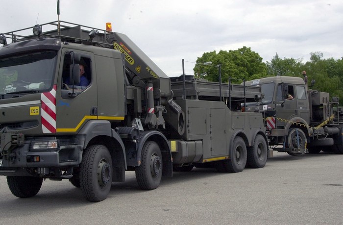Two military trucks, one towing the other