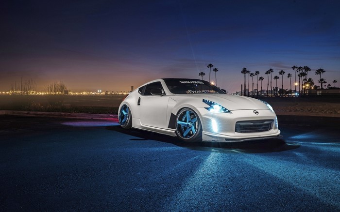 White Nissan 370Z sports car with blue wheels at night