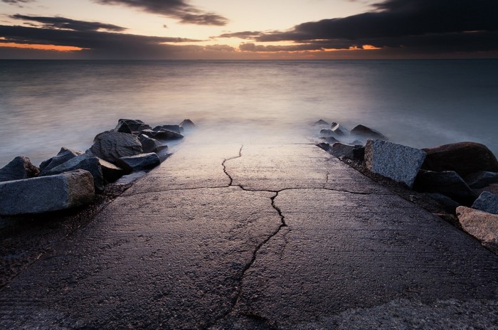 Concrete path leading to the sea at sunset
