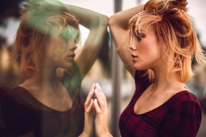 Woman with red hair reflected in glass