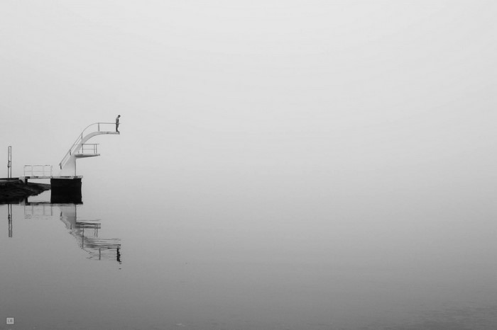 Person on diving board in fog over water