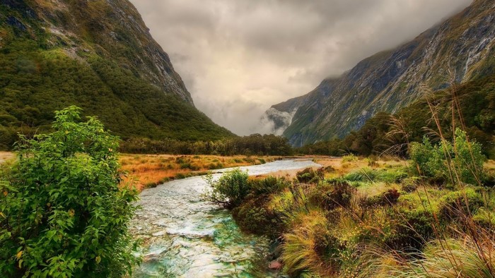 River flowing through a mountain valley with cloudy skies