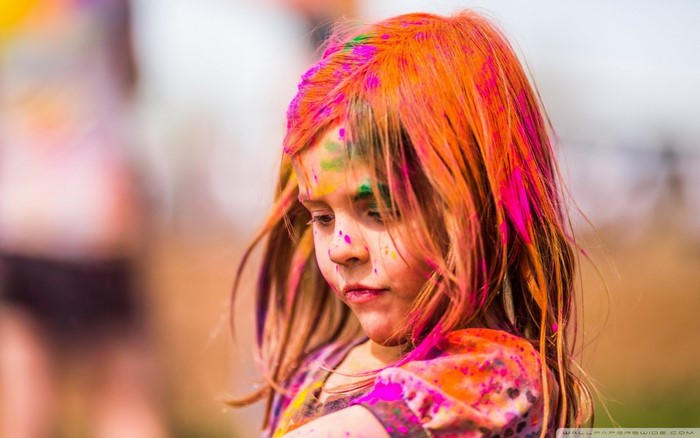 Young girl with colorful powder on her face and hair