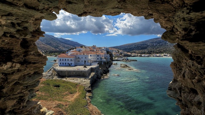 View of a coastal town through a rock arch