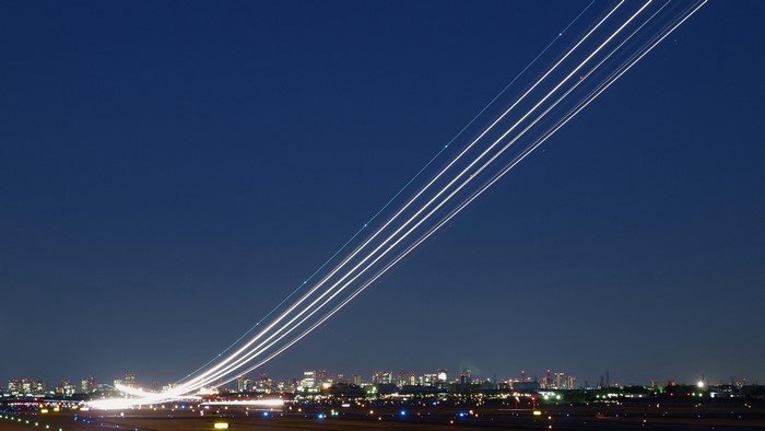 Airplane contrails over airport and cityscape at night