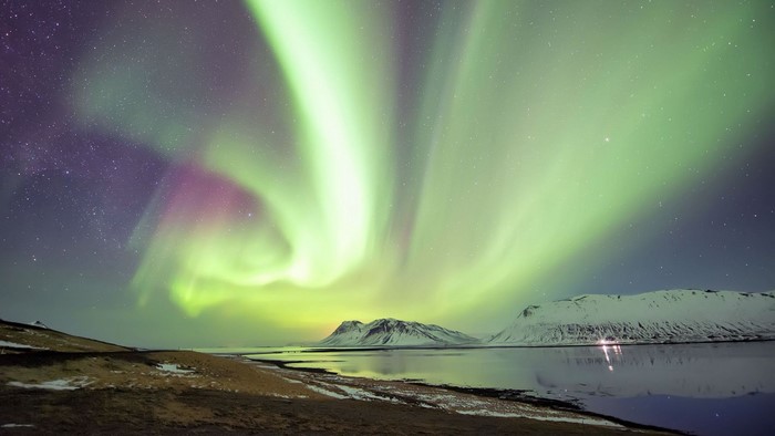 Aurora Borealis over a snowy landscape and water