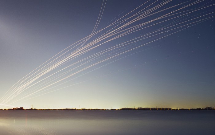 Airplane contrails over water at dusk