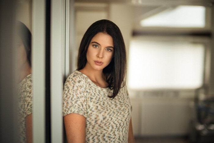 Woman leaning against a wall with reflection
