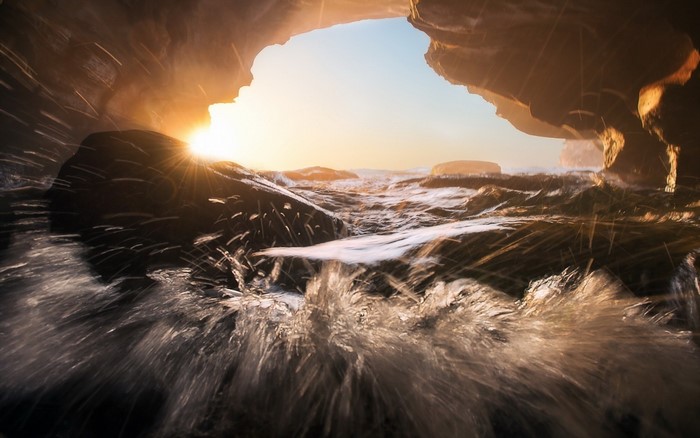 Sunset over ocean waves seen from a cave