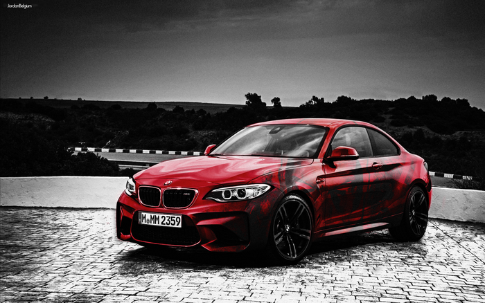 Red BMW M2 with custom graphics on paved surface