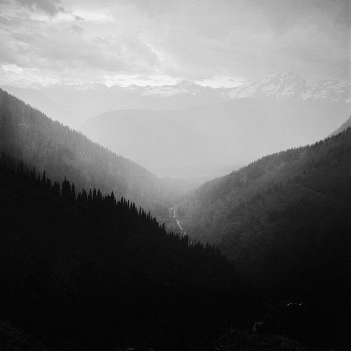 Misty mountain valley with a river and snow-capped peaks