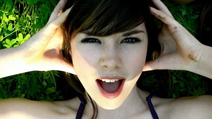 Woman with hands on head lying on grass