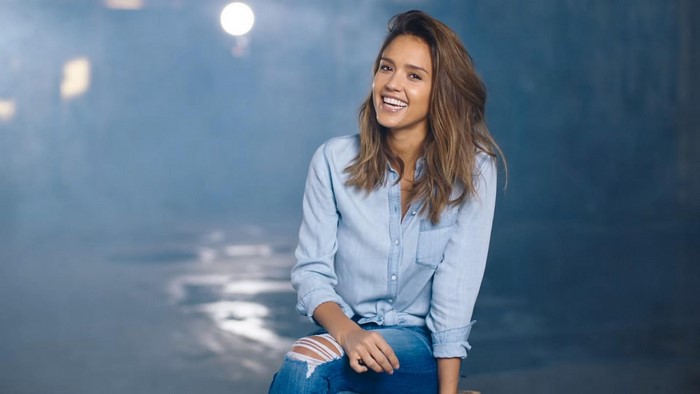 Jessica Alba sitting and smiling in a denim shirt