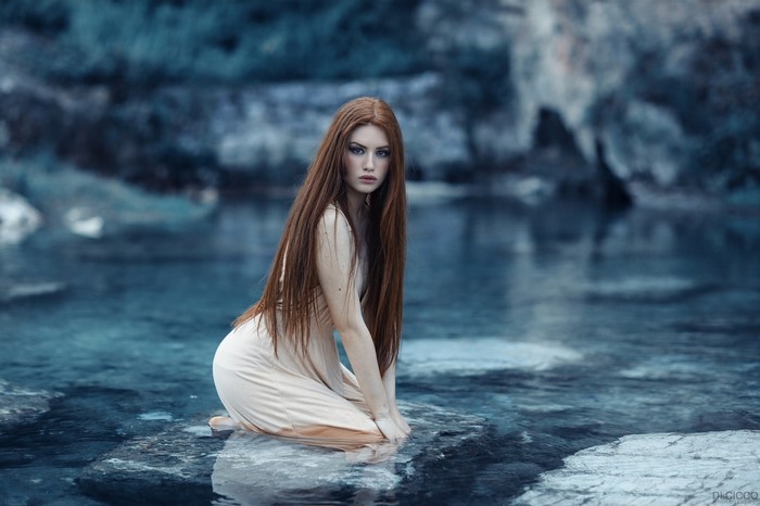 Redhead Woman Kneeling in Water with Blue Rocks