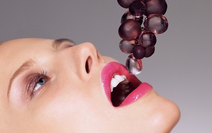 Woman with pink lips eating grapes