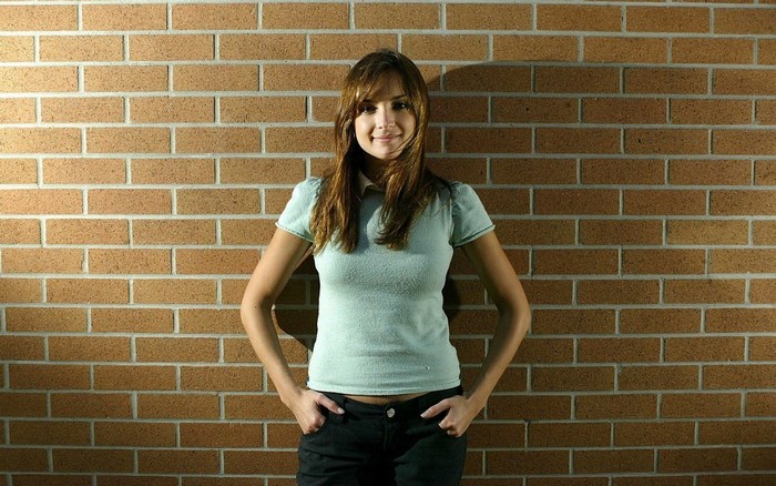 Rachael Leigh Cook standing in front of a brick wall