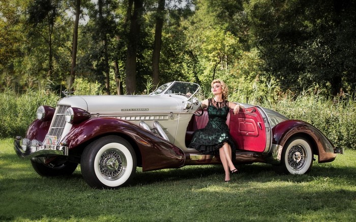 Woman in vintage dress posing with a classic convertible car
