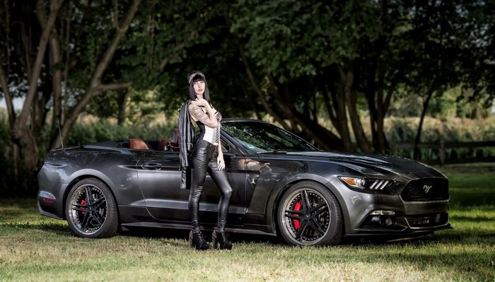 Woman in leather posing with a Ford Mustang convertible