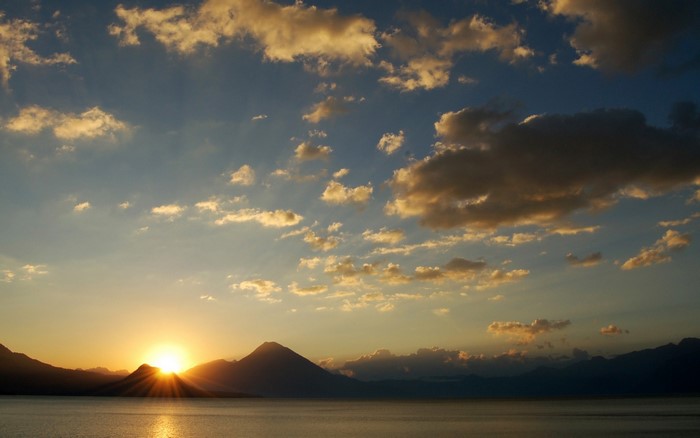 Sunset over a lake with mountains and clouds