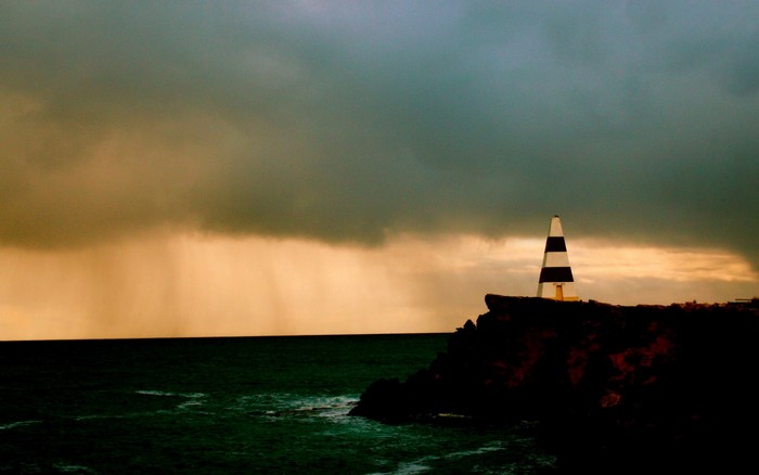 Lighthouse on a rocky coast during a storm