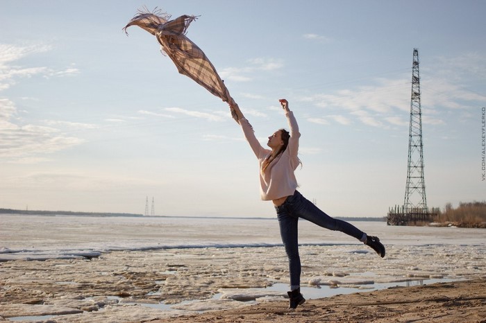 Woman with scarf jumping by frozen river
