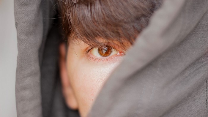 Close up of a person's eye peeking from a hoodie