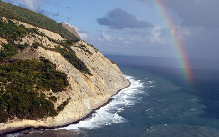 Cliff overlooking the sea with a rainbow