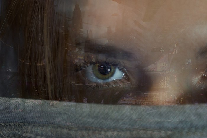 Double exposure of a woman's eye and a futuristic city