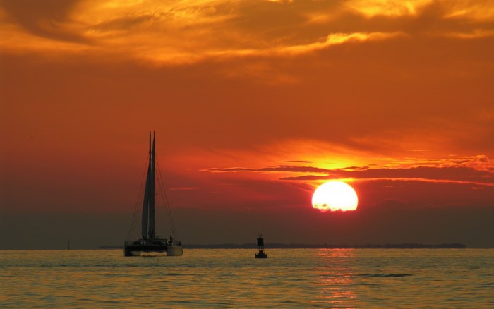 Catamaran sailing at sunset over the ocean