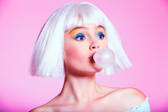 Woman with white wig blowing bubblegum