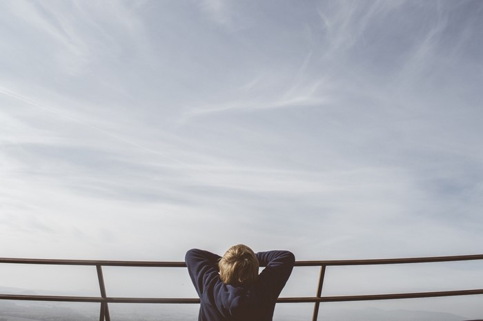 Person with hands behind head looking at sky