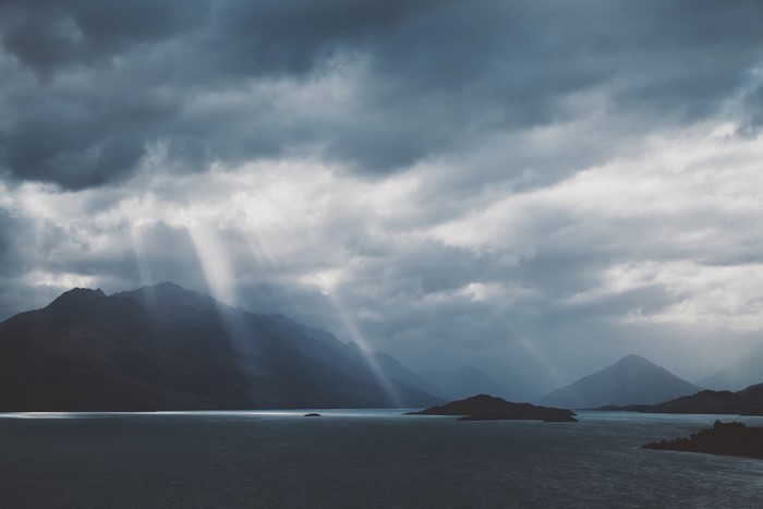 Sunbeams through clouds over mountains and lake