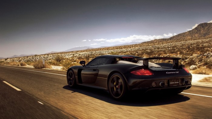 Black Porsche Carrera GT driving on a desert road