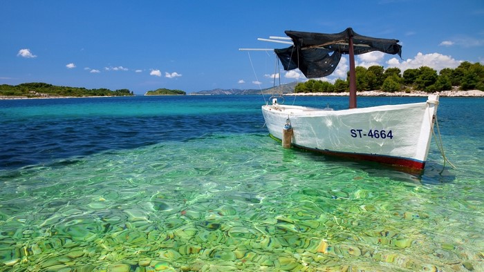 White boat moored in clear turquoise water near islands