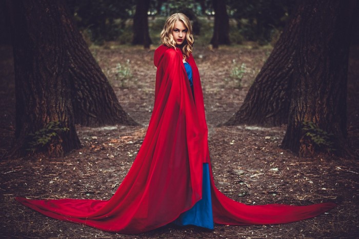 Woman in a red cape and blue dress in a forest