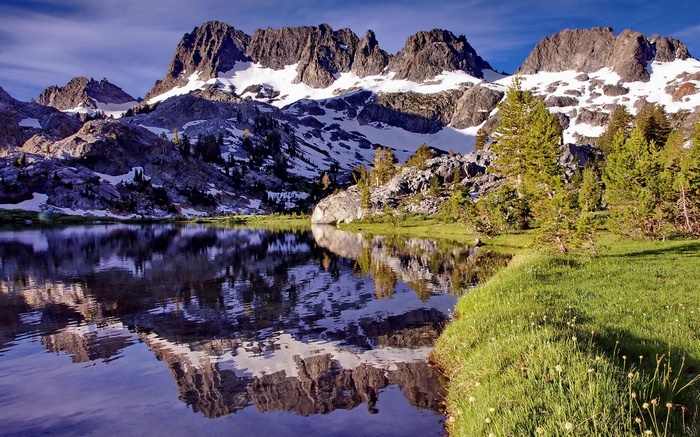 Mountain lake reflection with snow-capped peaks and pine trees