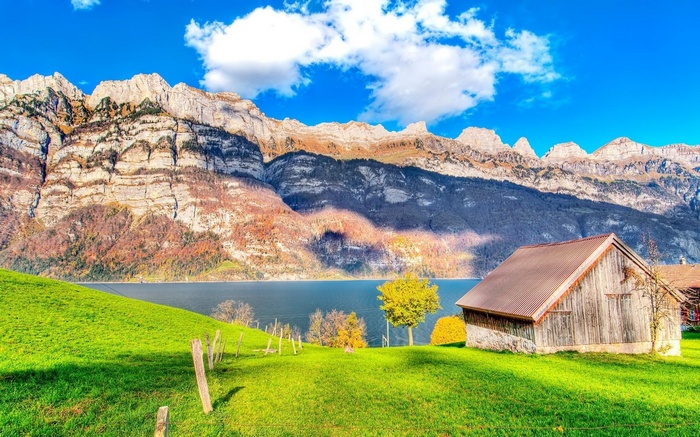 Wooden barn by a lake with mountains