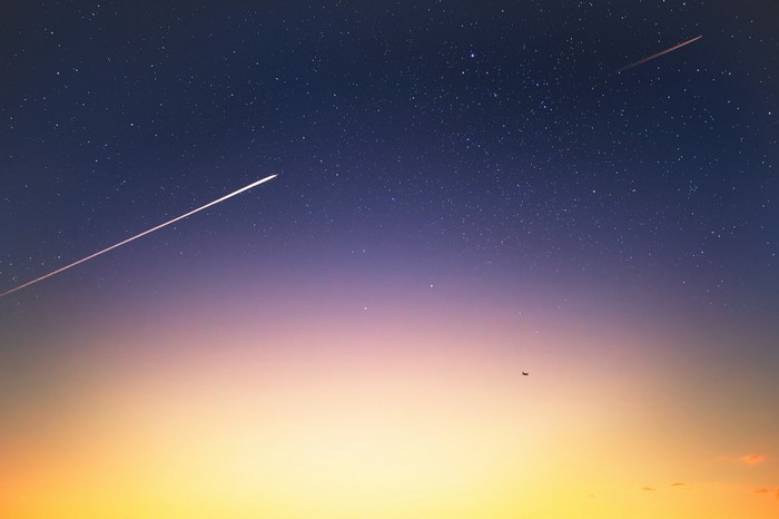 Airplane and contrails in starry twilight sky