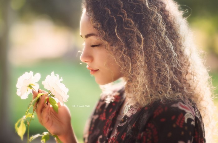 Woman smelling white flowers in sunlight
