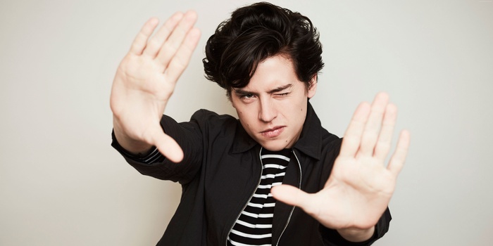 Cole Sprouse posing with hands up