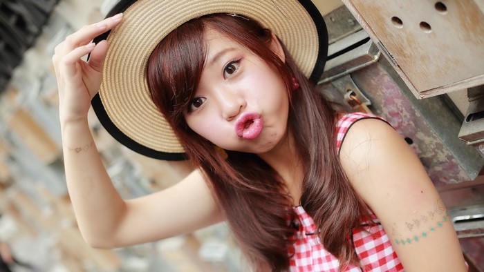 Young woman wearing a straw hat and red checkered dress
