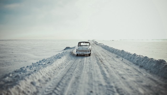 Vintage car driving on a snowy road