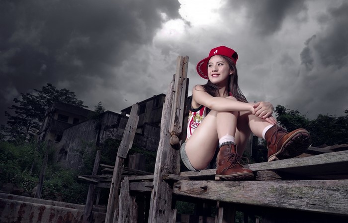 Woman in red cap and boots sitting on wooden structure