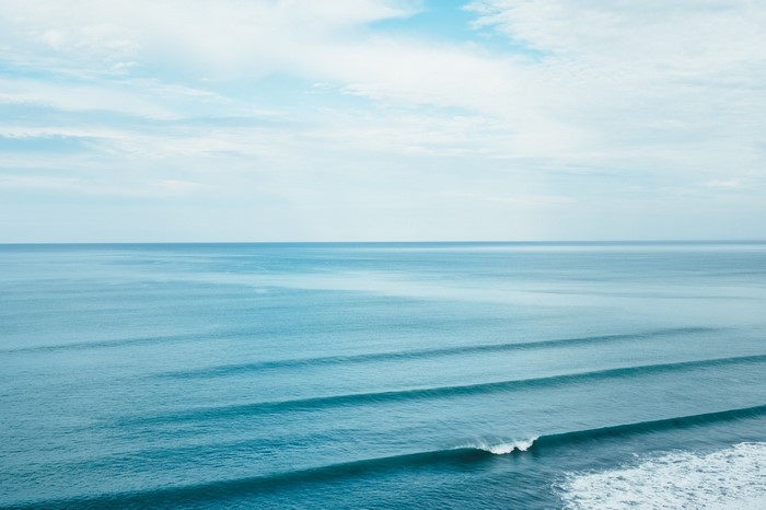 Ocean waves rolling towards the shore under a cloudy sky